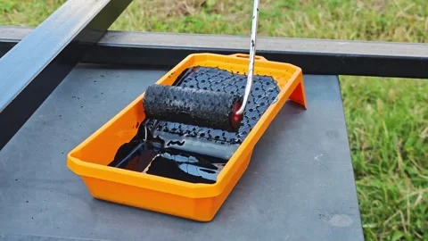 Paint roller dipping into black filled orange tray, preparing wall surface Видео 315358516