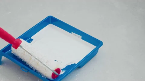 Paint roller dipping in white paint. Preparation for painting walls and ceiling. Stockbeeldmateriaal 148166867