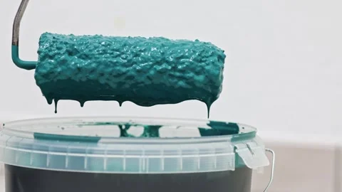 Paint roller drips vibrant teal paint into bucket, showcasing texture and color, Stock Footage 322134875
