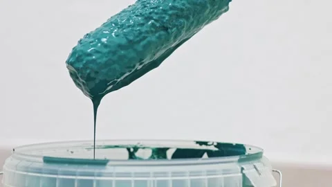Paint roller emerges from container, dripping teal paint, showcasing texture and Stock Footage 322134814