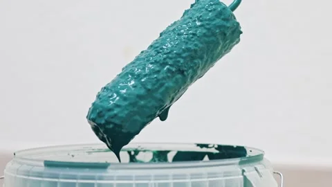 Paint roller emerges from teal paint bucket, showcasing vibrant texture and Stock Footage 322134896