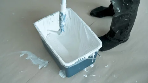 Paint roller gets readyt to be used in bucket full of fresh white paint Stock Footage 107271127