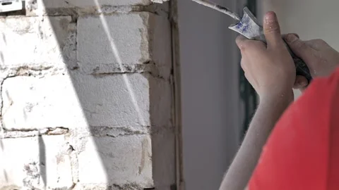 Paint roller in the hands of a man who applies a primer to a brick wall Stock Footage 206793538