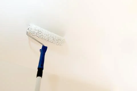 Paint roller on a long stick while painting a ceiling 스톡 사진