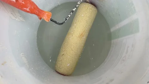 Paint roller with orange handle put inside white wet painting bucket Vidéo 213308981