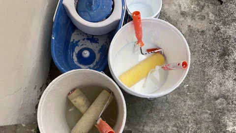Paint roller with orange handle put inside white wet painting bucket Vidéo 213308986