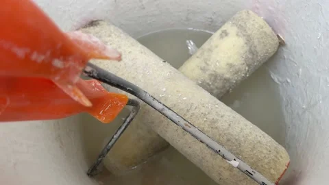 Paint roller with orange handle put inside white wet painting bucket Vidéo 213308991