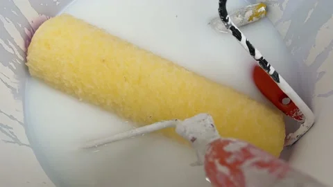 Paint roller with orange handle put inside white wet painting bucket Vidéo 213309056