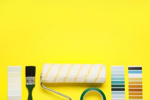 Paint roller with palette samples, brush and adhesive tape roll on yellow bac Stock-Fotos