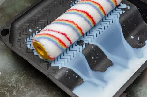 The paint roller is squeezed out in a plastic tray. The wall primer runs off. Stock Photos