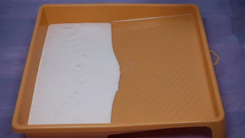The paint roller is wetted with white paint. Stock Footage 128508381