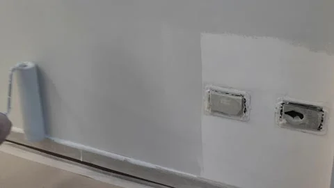 Paint roller with white paint paints a wall at home Video stock 130906117