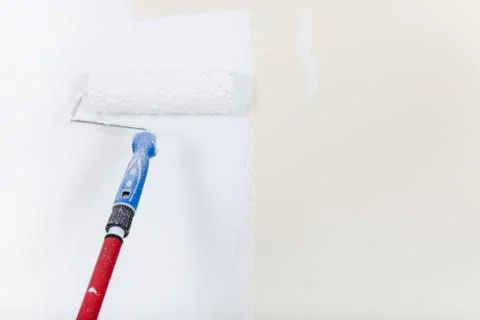 Paint roller on white wall Stock Photos