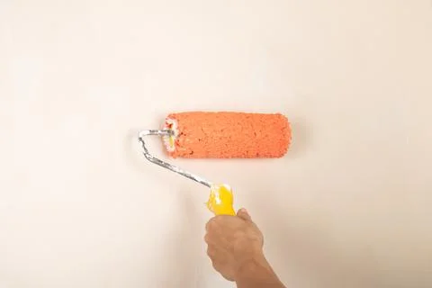 Paint roller in the worker's hand on the background of the wall Stock Photos
