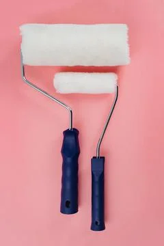 Paint rollers on a pink background Stock Photos