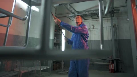 Paint shop worker moves structures for painting to a special spray booth Stock Footage 179706155