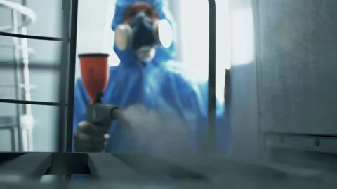 Paint shop worker in a protective uniform sprays a cloud of paint Stock Footage 179714590