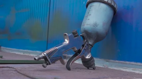 Paint spray gun lying on the table in an industrial painting workshop Stock Footage 306179654