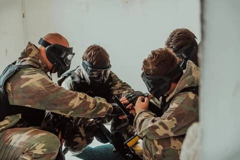 The paintball team agrees on tactics before the Stock Photos