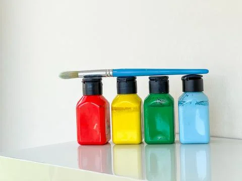 Paintbrush and four jars with bright colourful paint on a white background Stock Photos