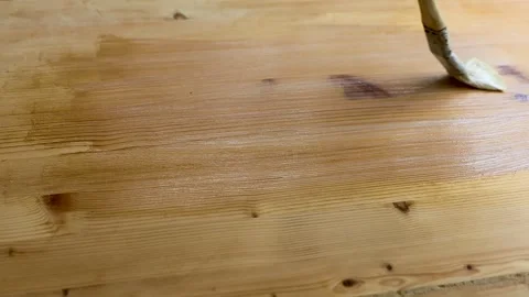Paintbrush applying clear varnish or protective coating to a wooden board Stock Footage 338232616