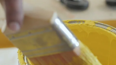 Paintbrush being dipped in can of yellow paint Stock Footage 56864145