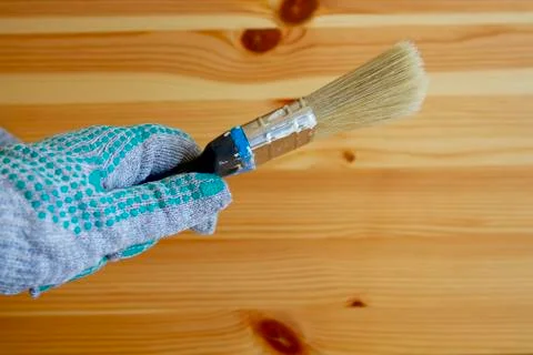 Paintbrush in the hand wearing working glove on the wooden table Stock Photos