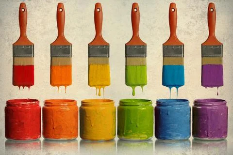 Paintbrushes dripping into paint containers Stock Photos