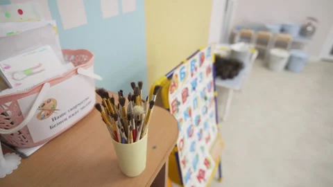 Paintbrushes stand in plastic cup on desk in classroom Stock Footage 310241811