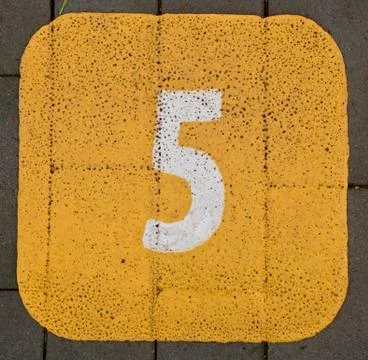 Painted 5 five on a pavement yellow background Stock Photos