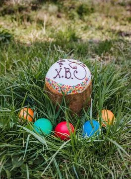 Painted and decorative Easter cake and eggs in the grass. Top view, copy spac Stock Photos
