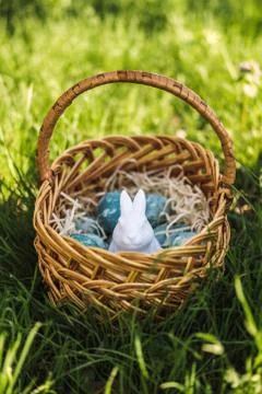 Painted blue textured easter eggs and a white plastic rabbit in a wicker brown Stock Photos