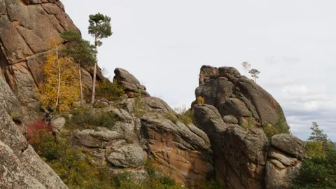 Painted brown rocks with trees growing on them under an overcast sky. Video stock 310492393
