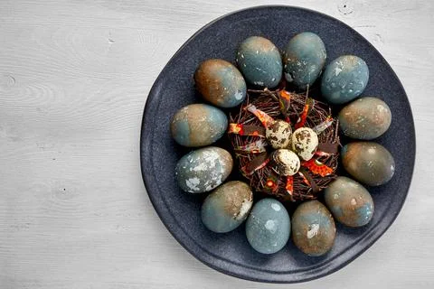 Painted chicken and quail eggs on a dark platter Stock Photos