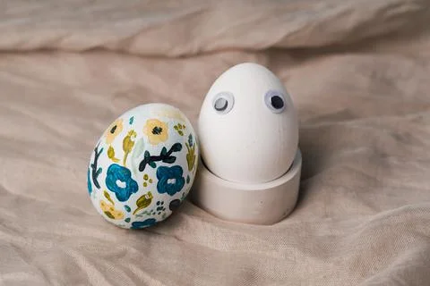 Painted chicken egg in floral pattern with white egg with doll eyes. craft for Foto stock