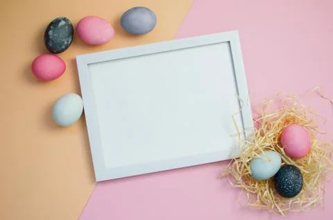 Painted colorful Easter eggs on pink and yellow background and frame for text Stock Photos
