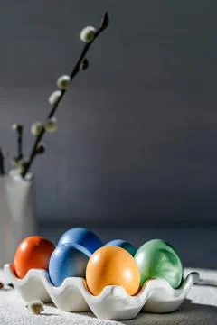 Painted colorful Easter eggs in a stand, a vase with a willow branch Stock Photos