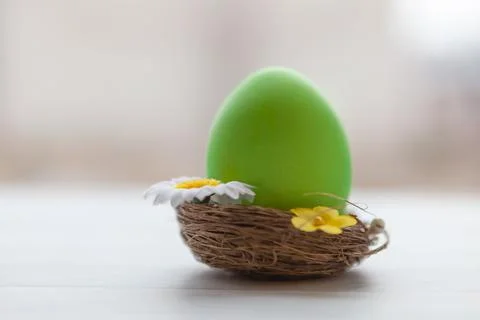 Painted Easter egg in a basket on a light wooden background 写真素材