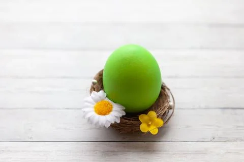 Painted Easter egg in a basket on a light wooden background, top view Stock Photos