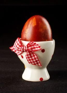 Painted Easter egg in the egg cup on the black background Stock Photos