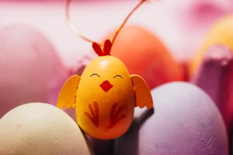 Painted Easter egg in a form of a cute funny yellow toy chicken. Colorful eggs Stock Photos