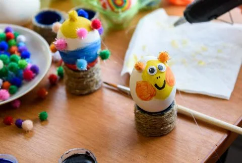 Painted easter egg with glued eyes stands on the table Foto stock