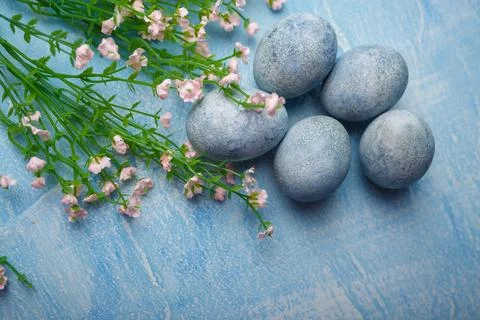 Painted Easter eggs on blue background with pink flowers. Spring holiday Stock Photos