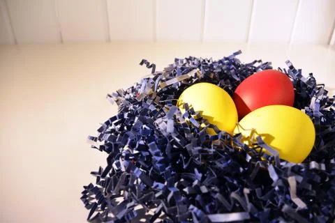 Painted Easter eggs in blue paper bird nest on white Stock Photos