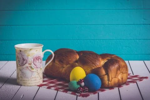 Painted Easter eggs, delicious cake and cup for milk on a wooden background. Eco Stock Photos