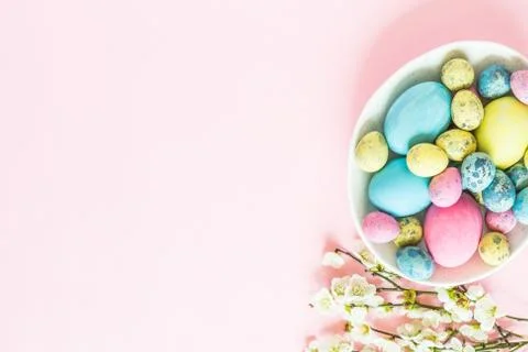 Painted easter eggs, floral branches, nest lying on pink background Foto stock