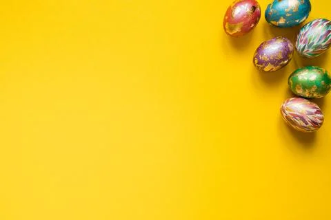 Painted Easter eggs with golden foil on the yellow background. Copy space. Stock Photos