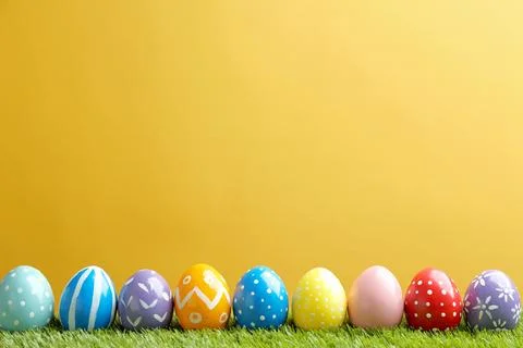 Painted Easter eggs on green grass against color background, space for text Stock Photos