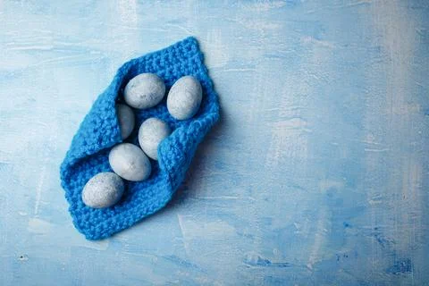 Painted Easter eggs on knitted pad on blue background. Spring holiday, symbol Stock Photos