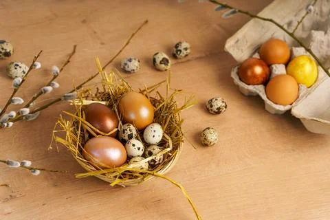 Painted Easter eggs lie in wicker basket on wooden tabletop. are spring flowers Stock Photos